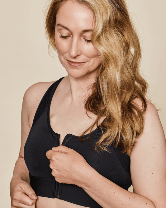 Black sports bra with front zipper and supportive racerback straps, side close-up