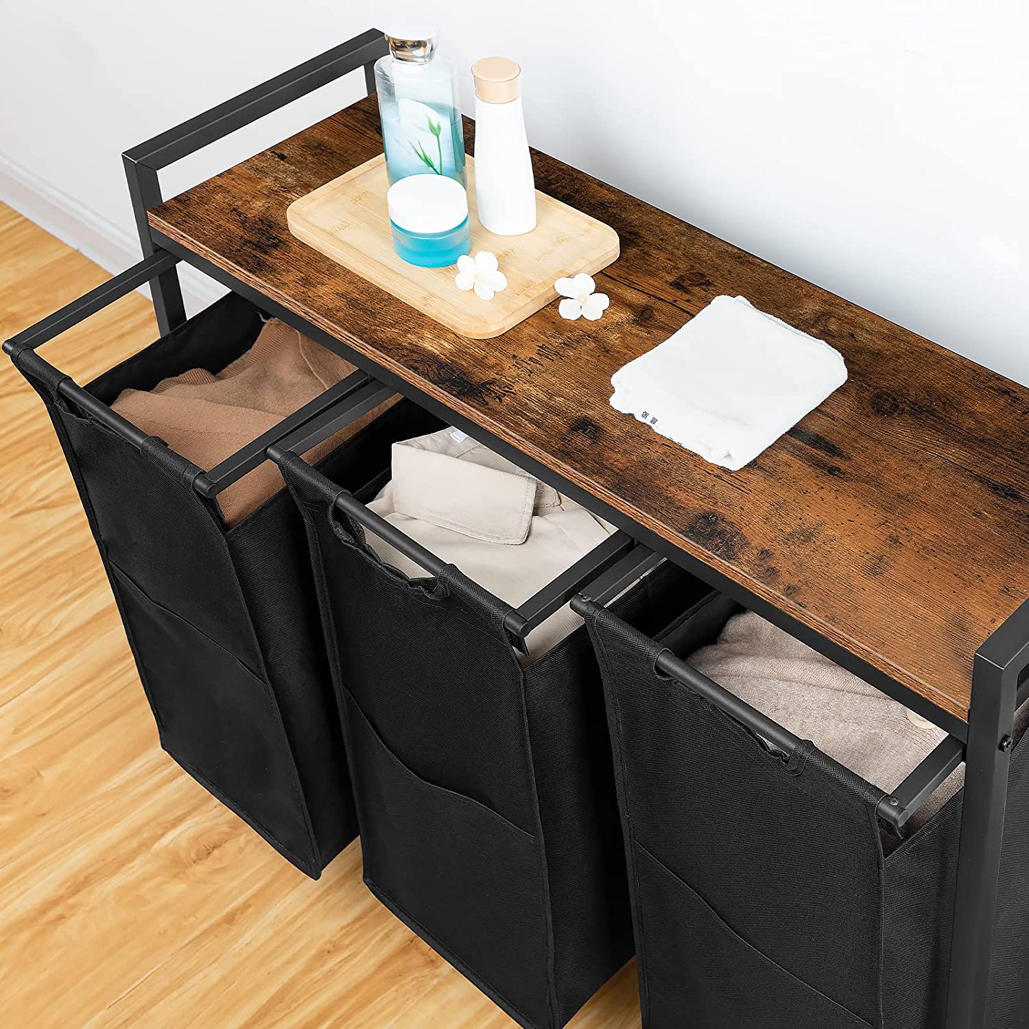 Rolling laundry hamper cart with three black fabric compartments and a wooden top shelf.