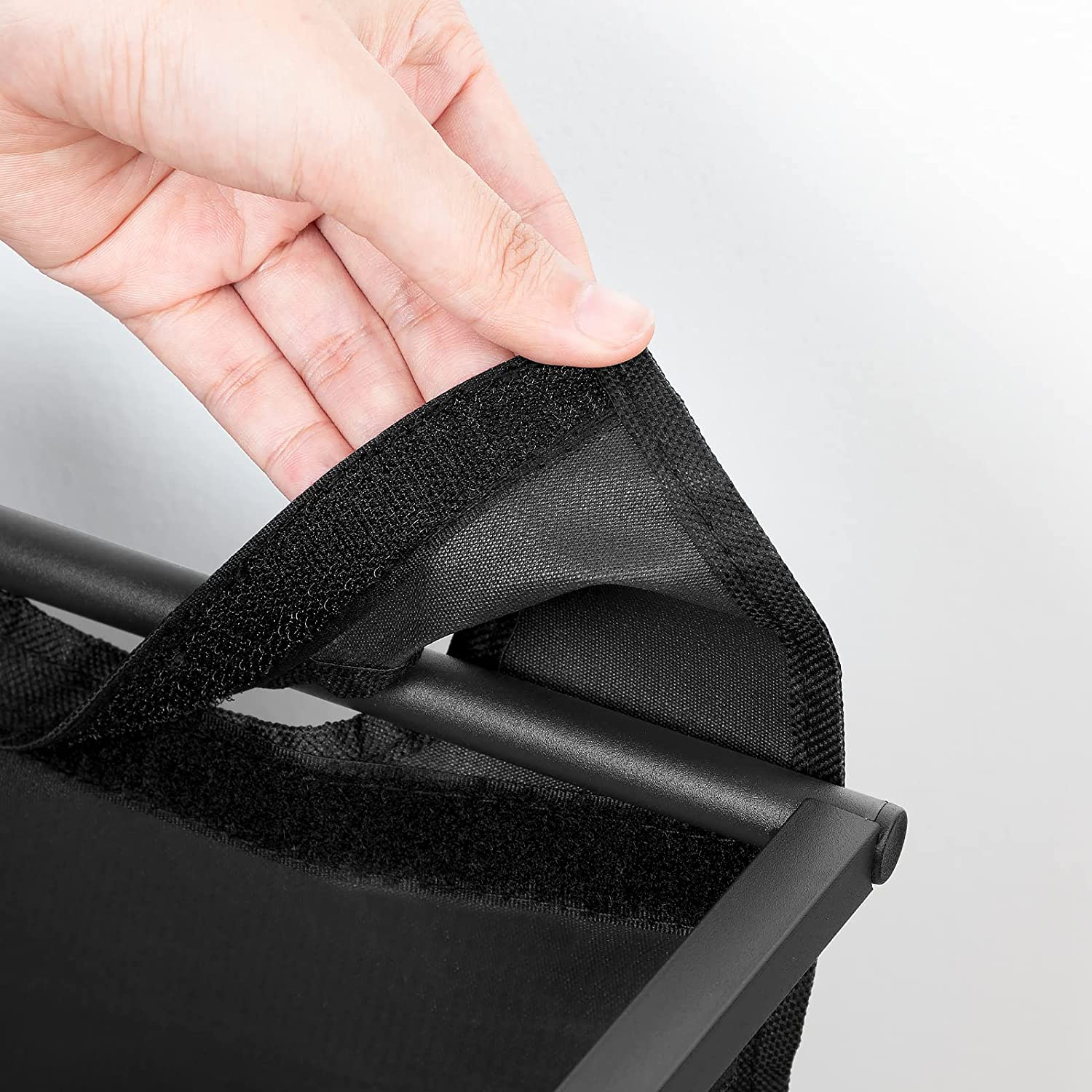 Close-up of dark fabric laundry bag handle on a rolling 3-compartment hamper cart.