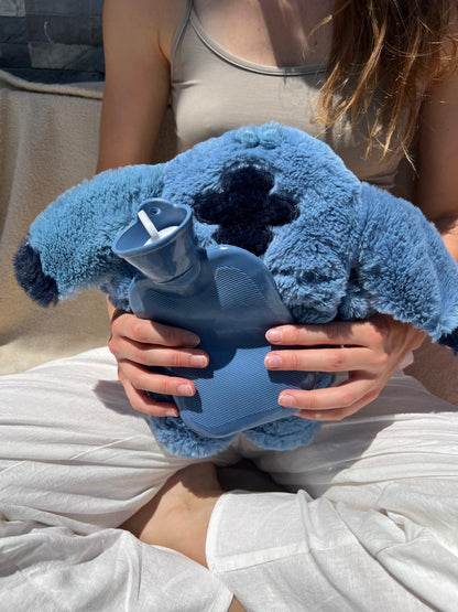 Blue plush cartoon hot water bottle in hands, blue cover over bottle with screw cap