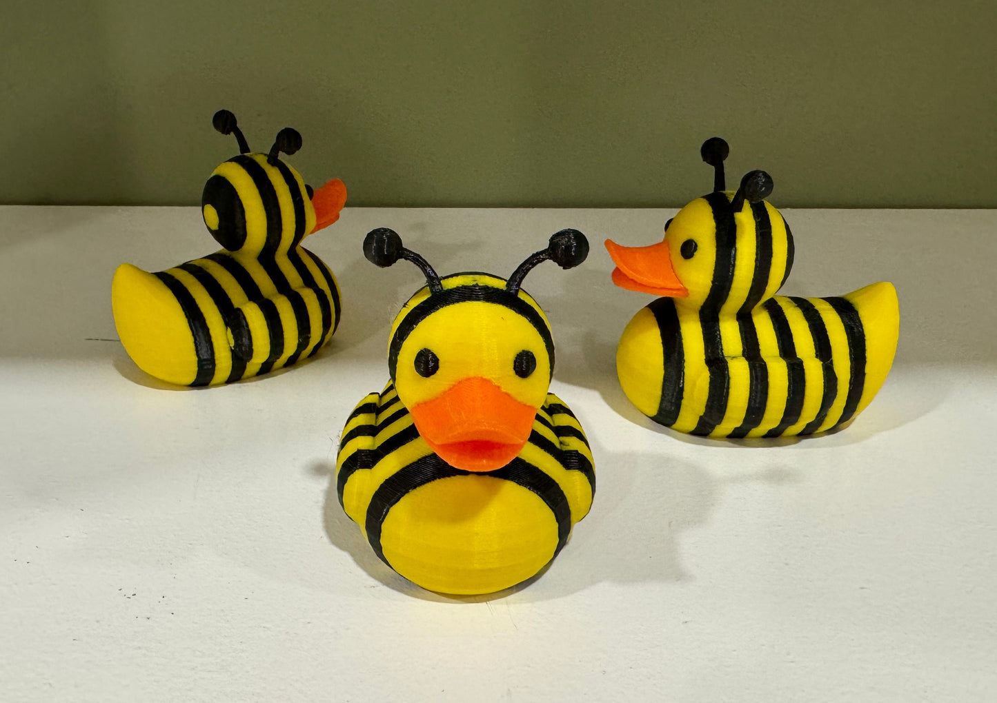 Plush bee-striped duck toy with orange beak and yellow-and-black body