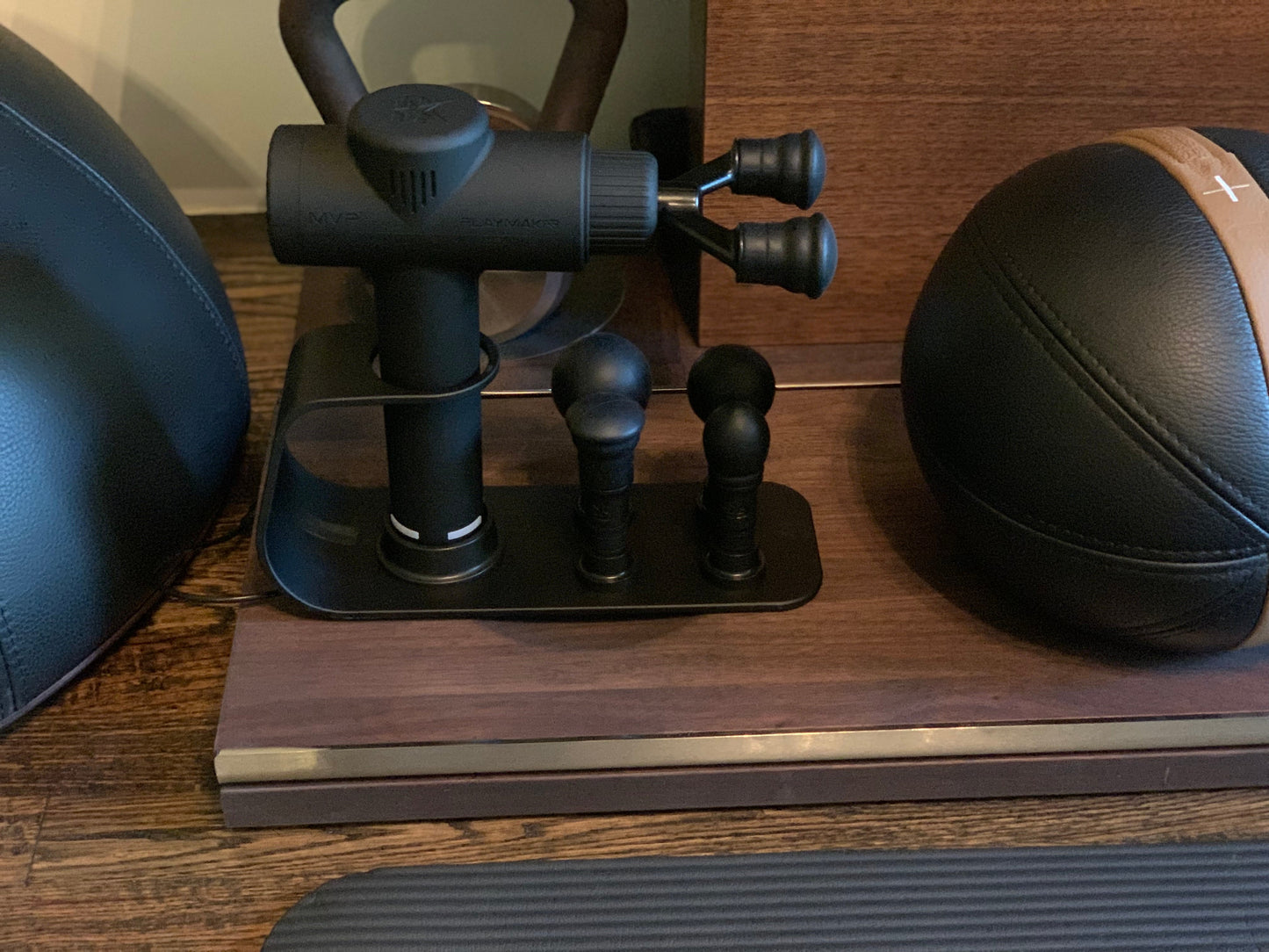 Black charging dock with four massage heads on a wood surface, close-up