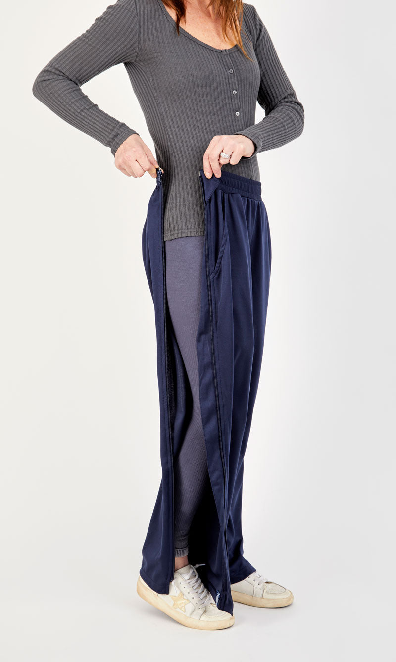 Woman wearing a gray long-sleeve top and navy wide-leg pants on a white background