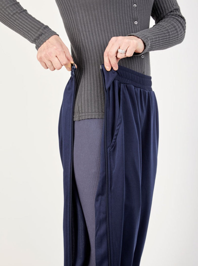 Person wearing a gray ribbed sweater and navy blue pants on a white background