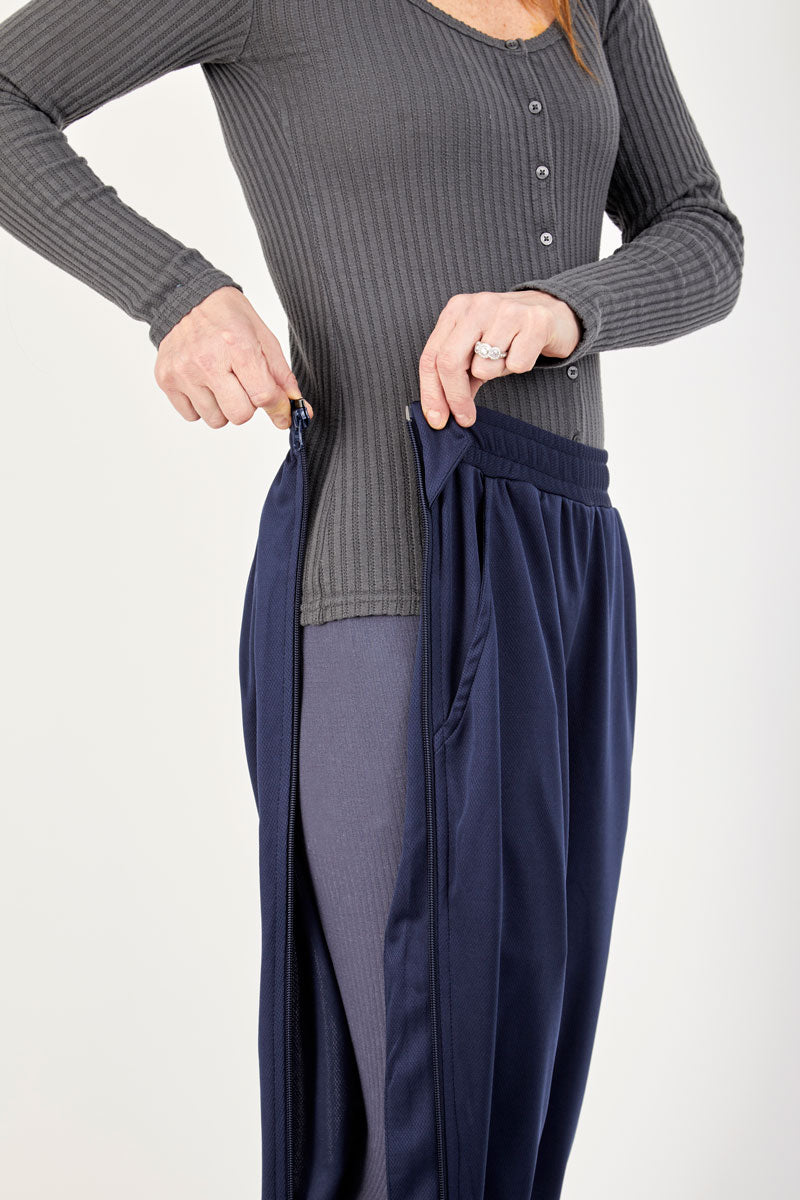 Person wearing a gray ribbed long-sleeve top and navy pants on a white background