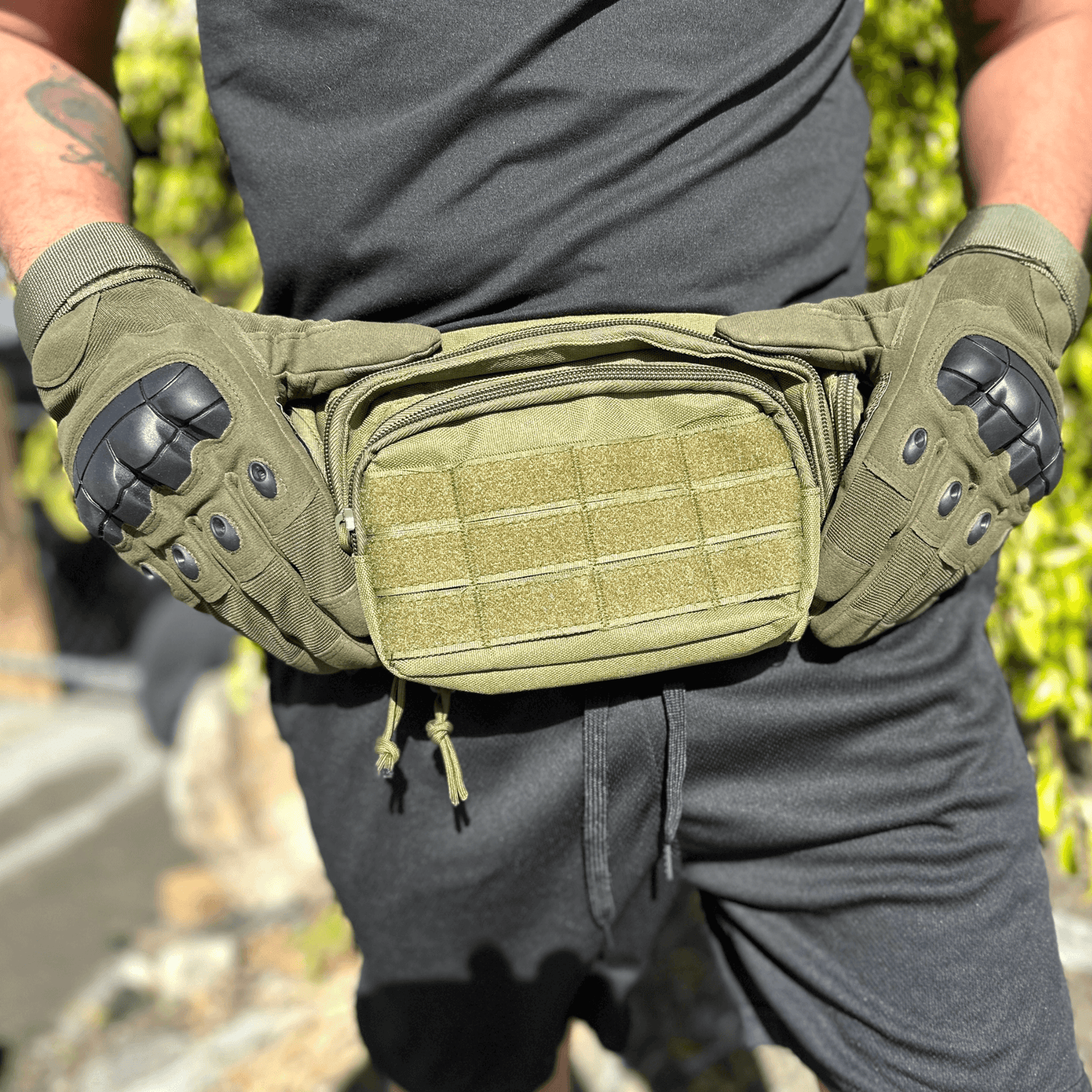 Tan tactical gloves worn by a person, showing knuckle guards and front pouch detail.