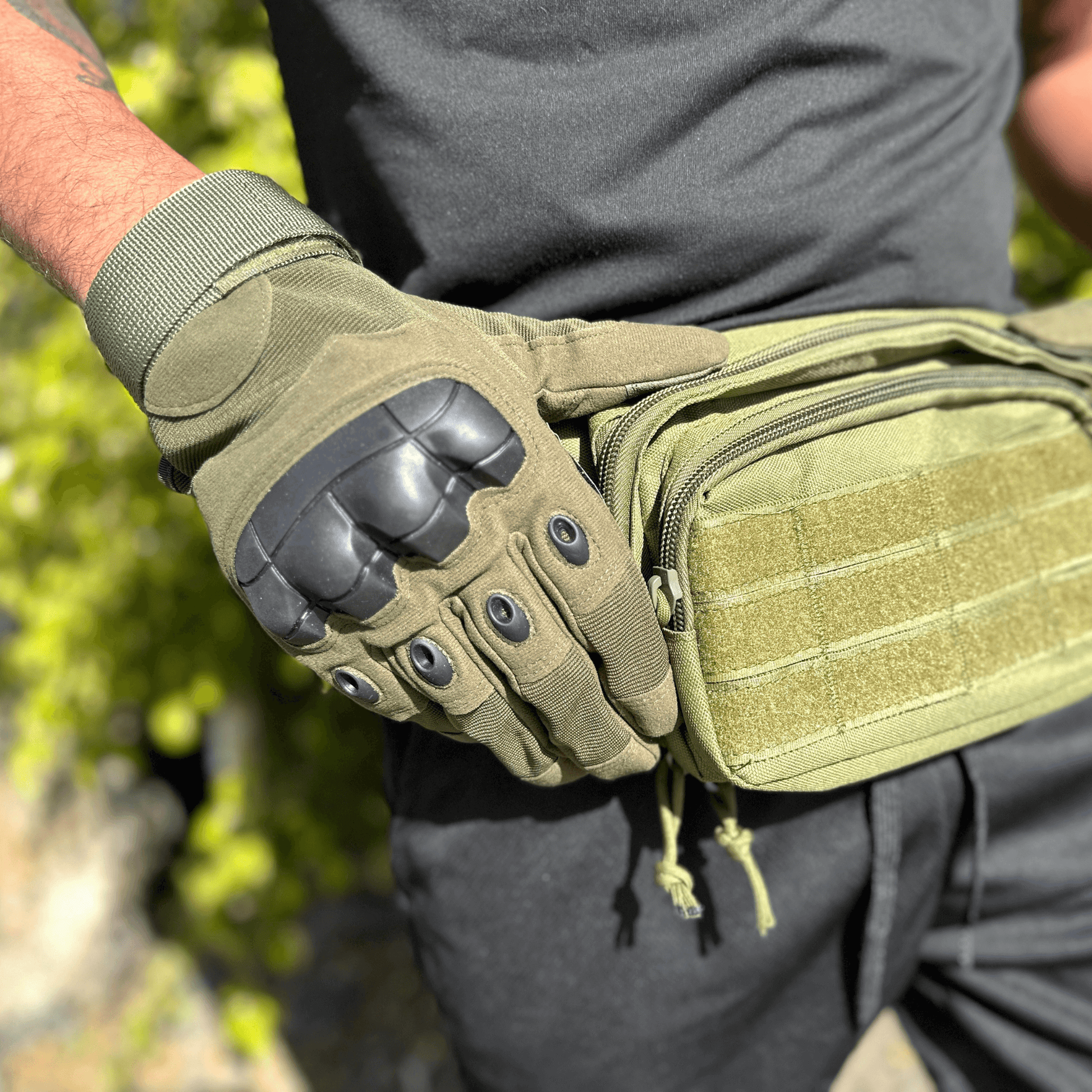 Tan tactical gloves with reinforced palm and black knuckle armor; close-up on hand.