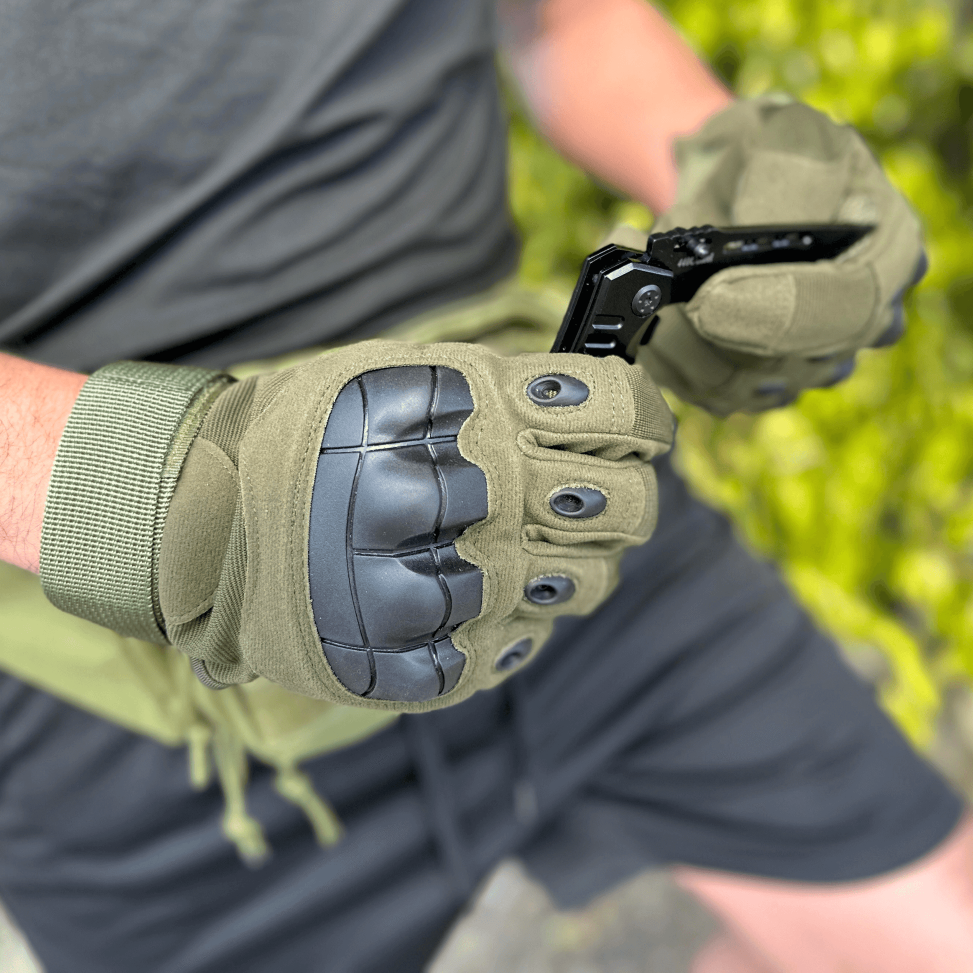 Tan tactical gloves with black knuckle protection and finger gussets, gripping gear.