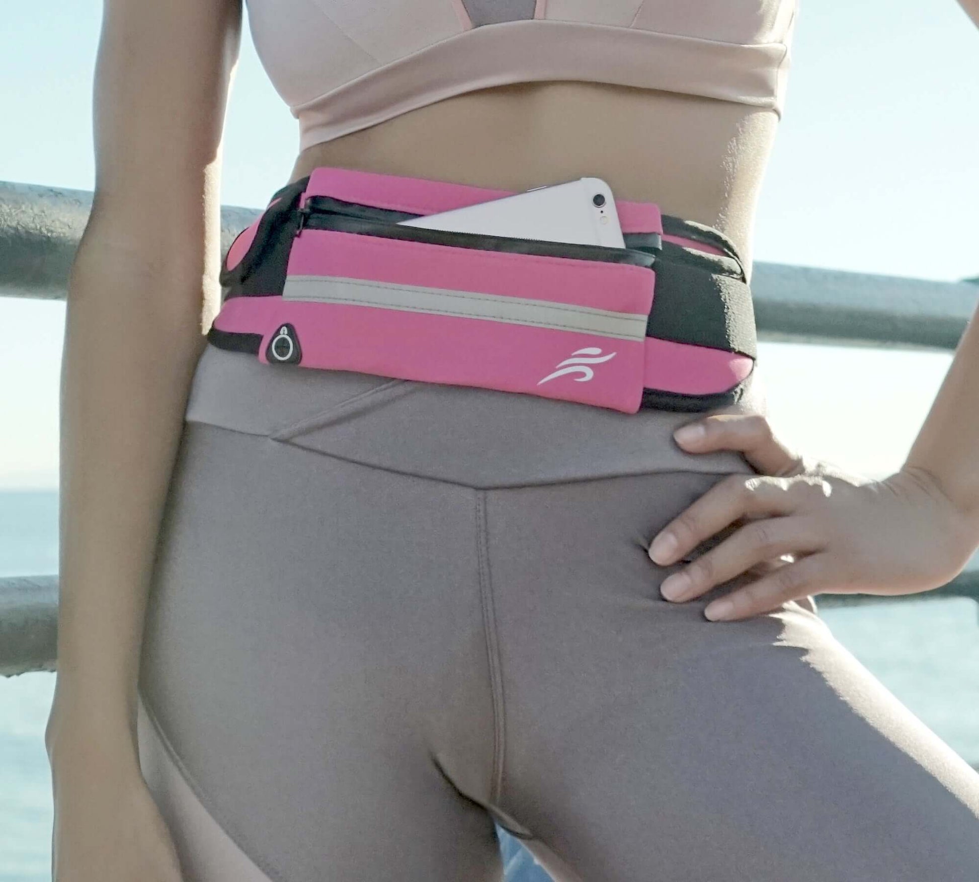 Pink sports running belt fanny pack worn at waist with front zip pouch
