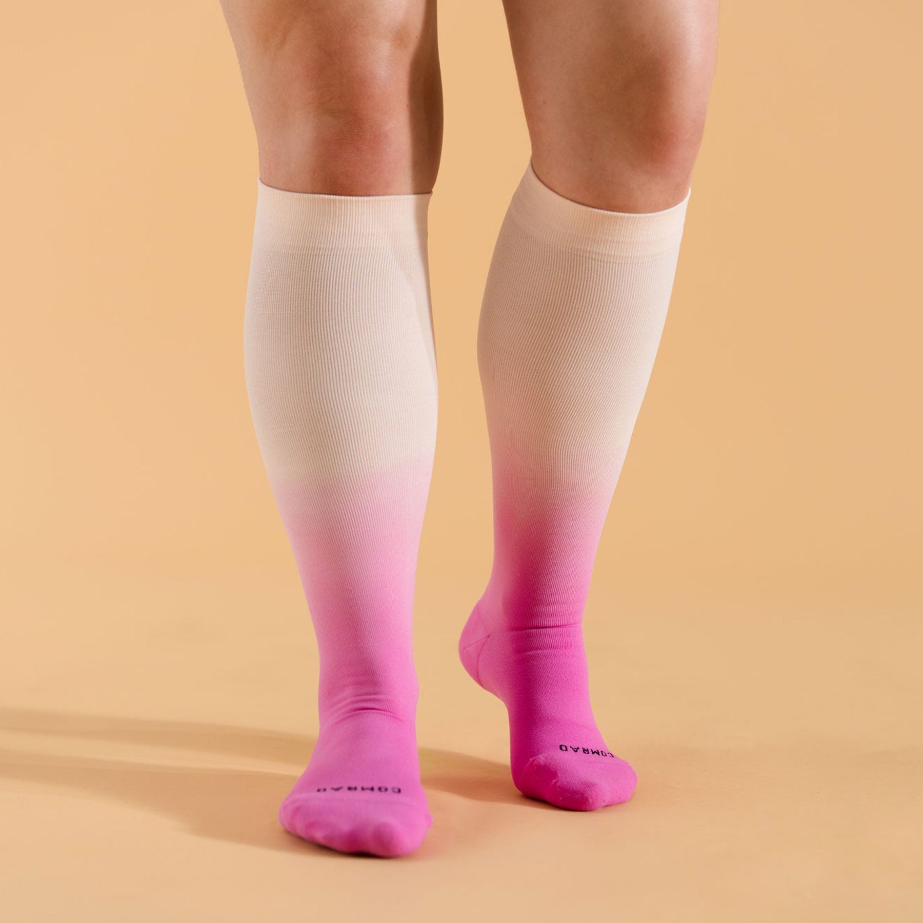Pair of knee-high berry ombre compression socks on legs, pink-to-fuchsia gradient