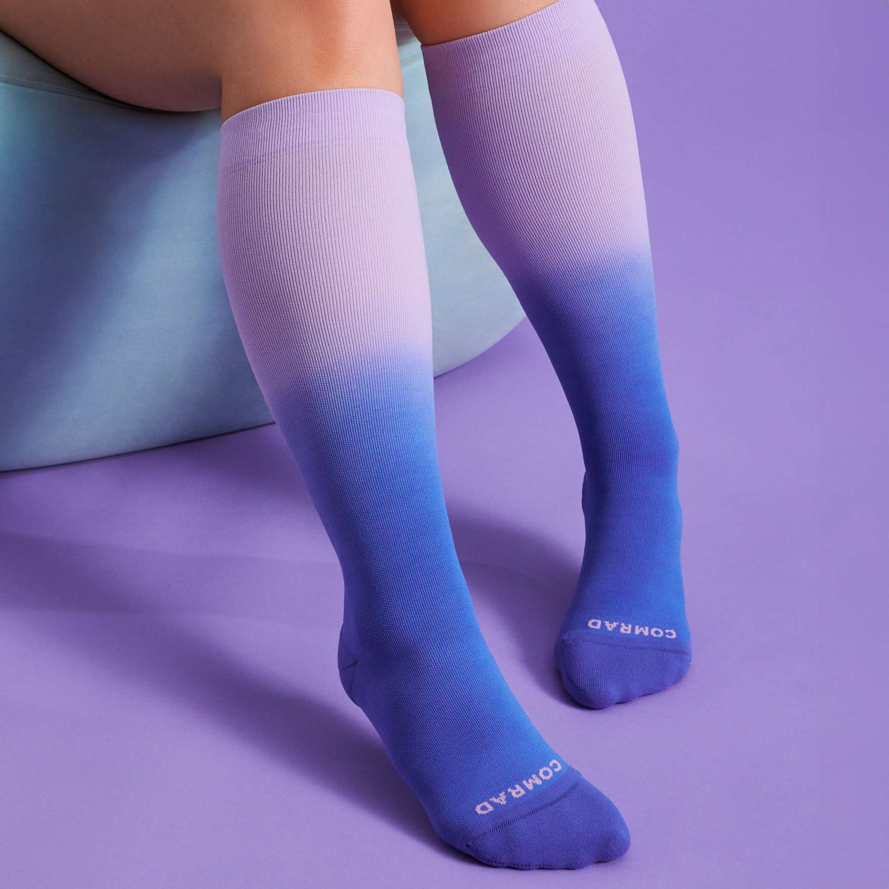 Knee-high ombre compression socks, purple-to-blue gradient, worn with cushioned foot