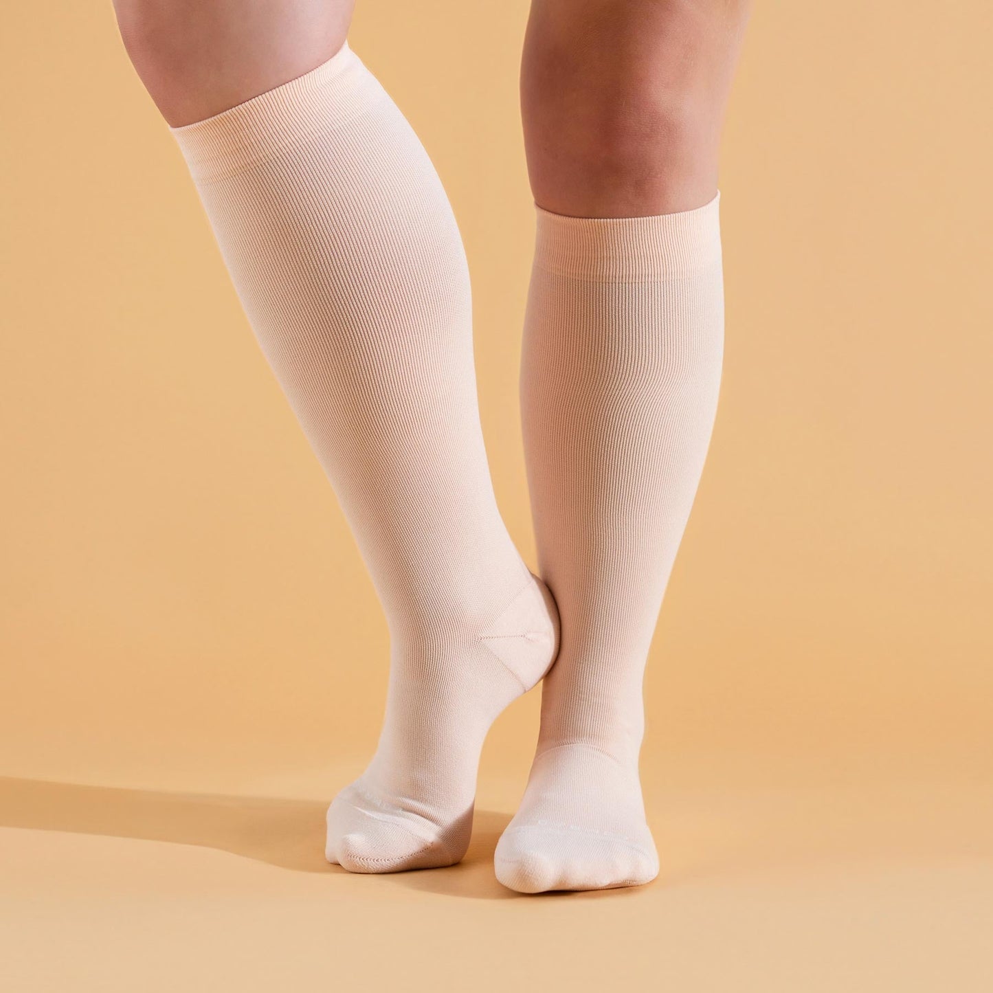 Knee-high compression socks in light cream on feet, full length coverage