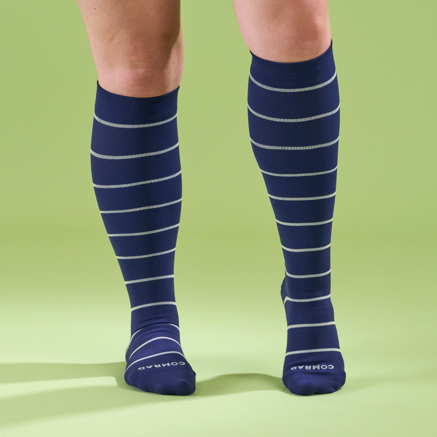 Knee-high compression socks on legs, navy blue with light stripe bands
