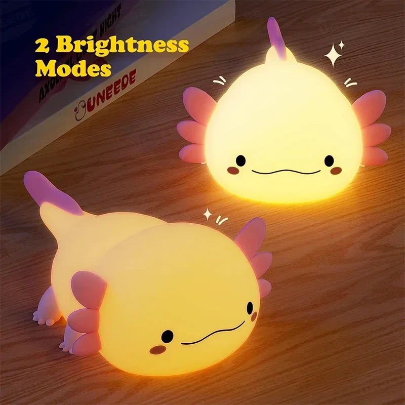 Two glowing cream axolotl night lights with pink fins on a wooden surface