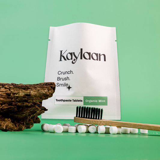 Fluoride toothpaste tablets trial pack pouch with tablets and toothbrush on a wooden tray