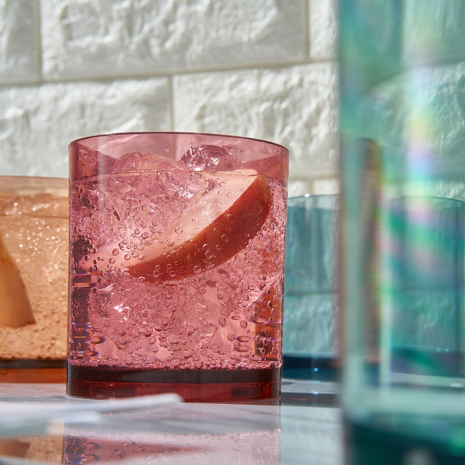 Translucent red acrylic lowball glass with ice and citrus slice