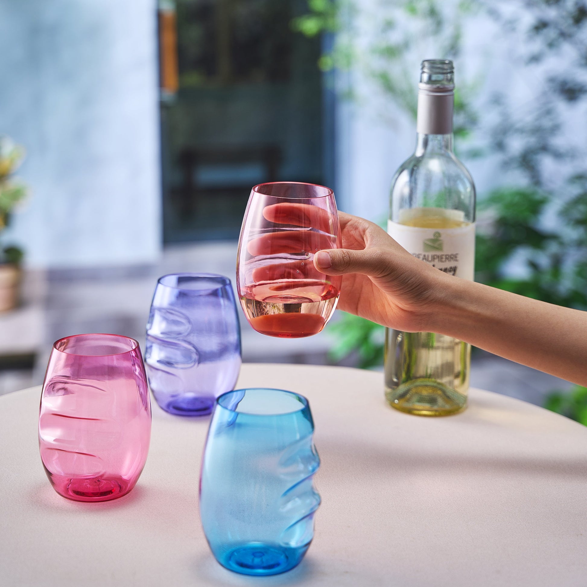 Pink acrylic stemless wine glass with red wine; other assorted glasses in set of 4