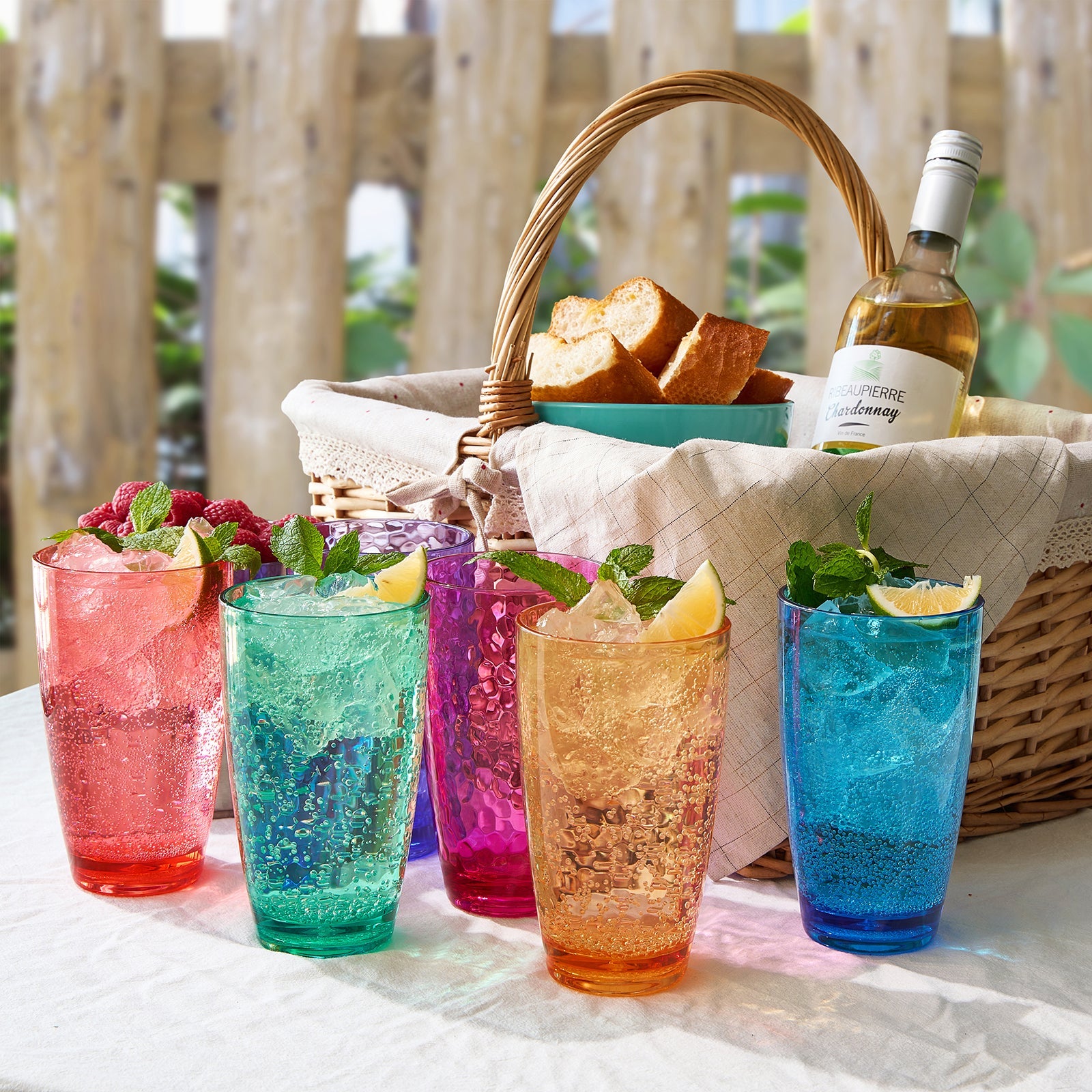 Set of 6 colored acrylic highball glasses with ice and citrus, on a table