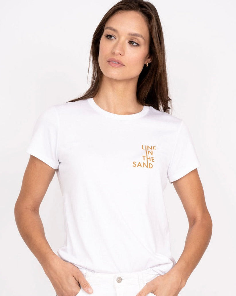 White crew-neck graphic tee with orange 'LINE IN THE SAND' text on chest