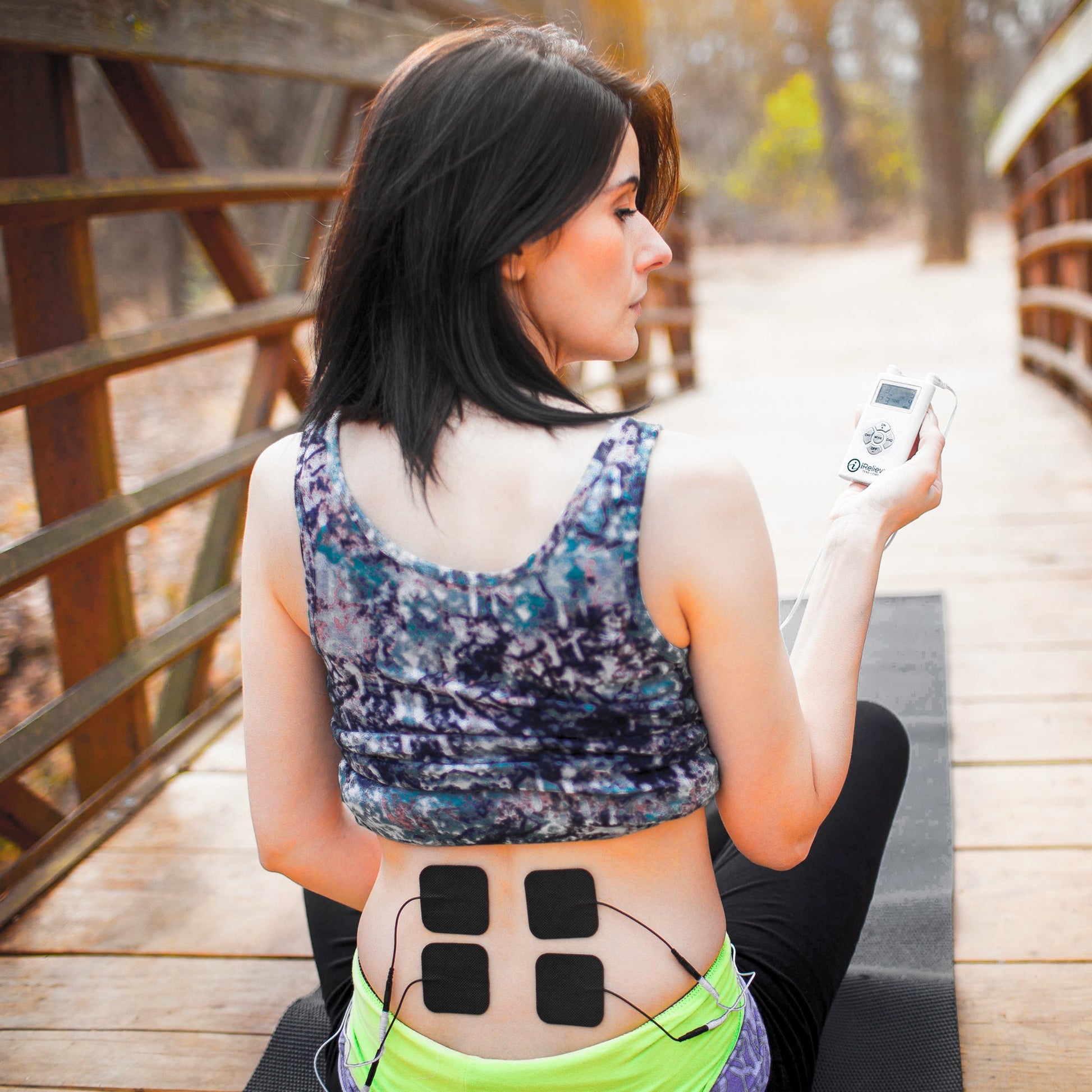 Black electrode pads attached to abdomen with thin cables for stimulation