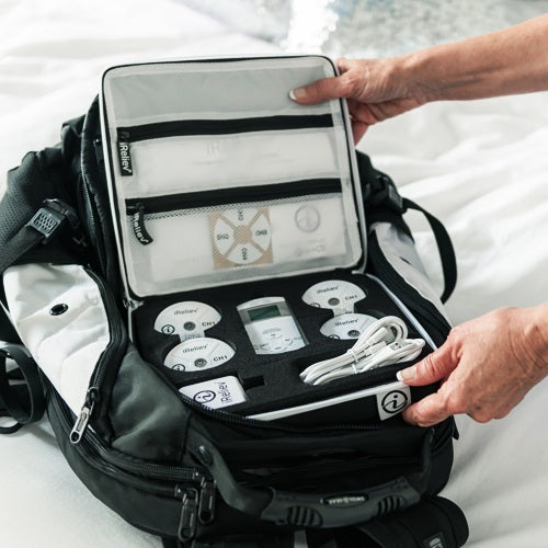 Hard carry case open and held, showing iReliev pods, remote display, and cables