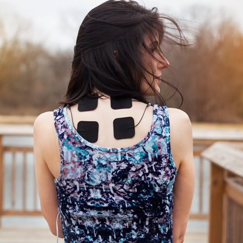Electrode pad strap on a woman’s back with black square TENS pads