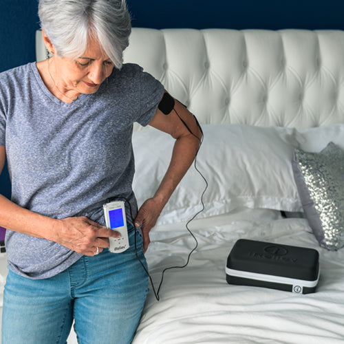 Wired TENS+EMS device being used on a body area with gel pads and controller display