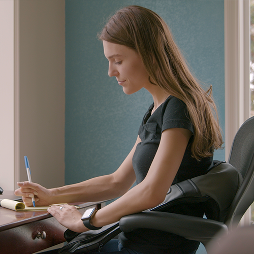 Shiatsu neck and back massager worn on shoulders by a seated person at home