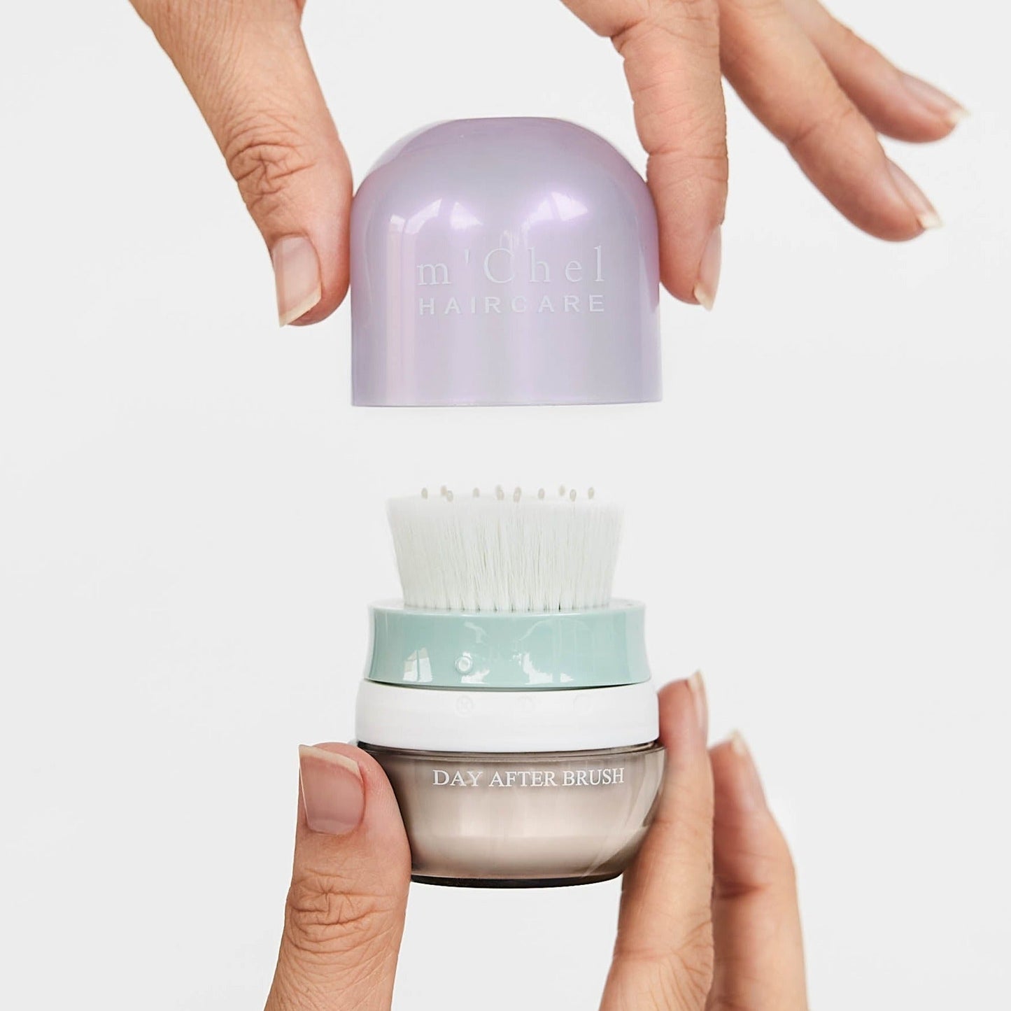 Hair brush jar upside down with lavender cap held above teal-and-white bristles