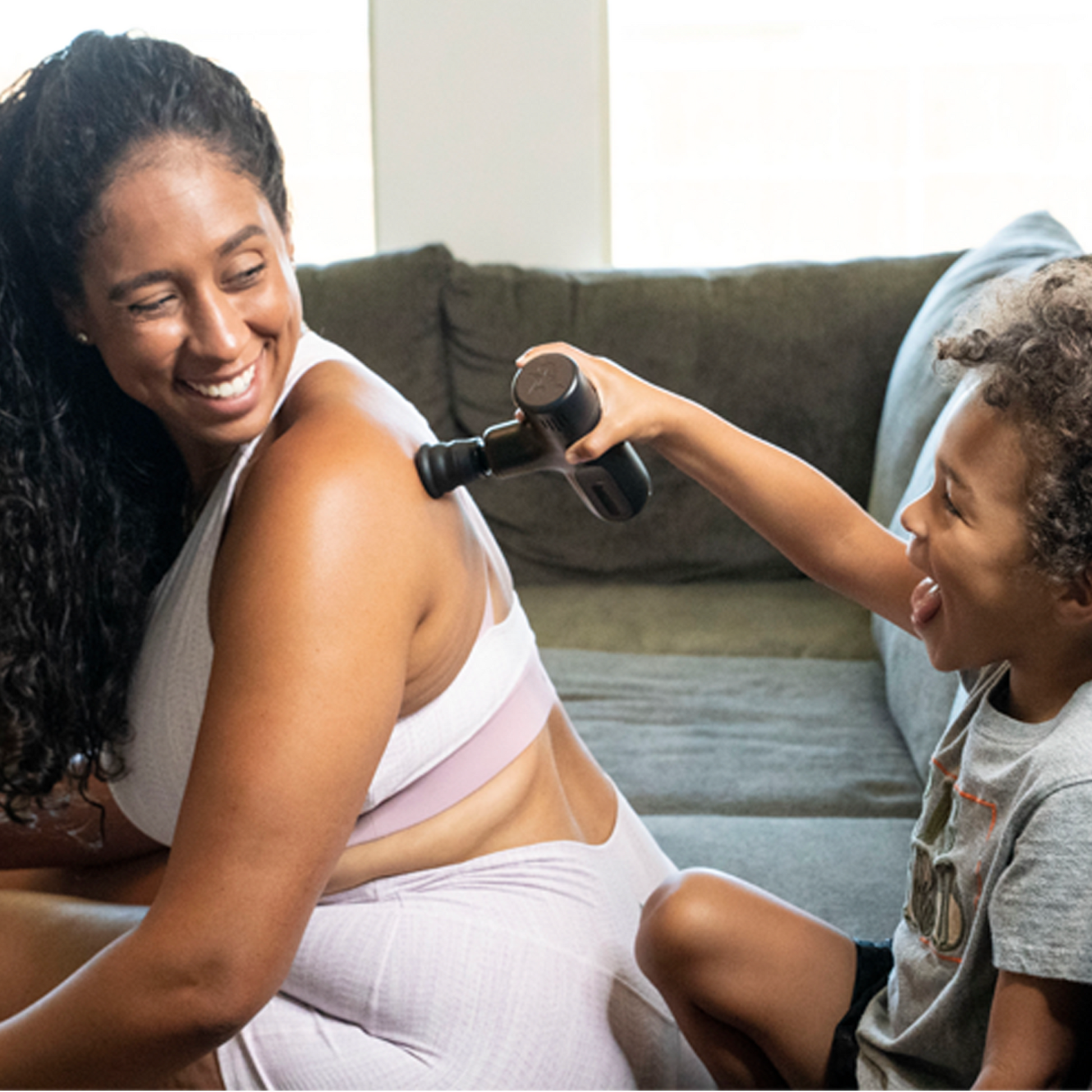 Percussion massage gun in use on a person’s shoulder and upper arm