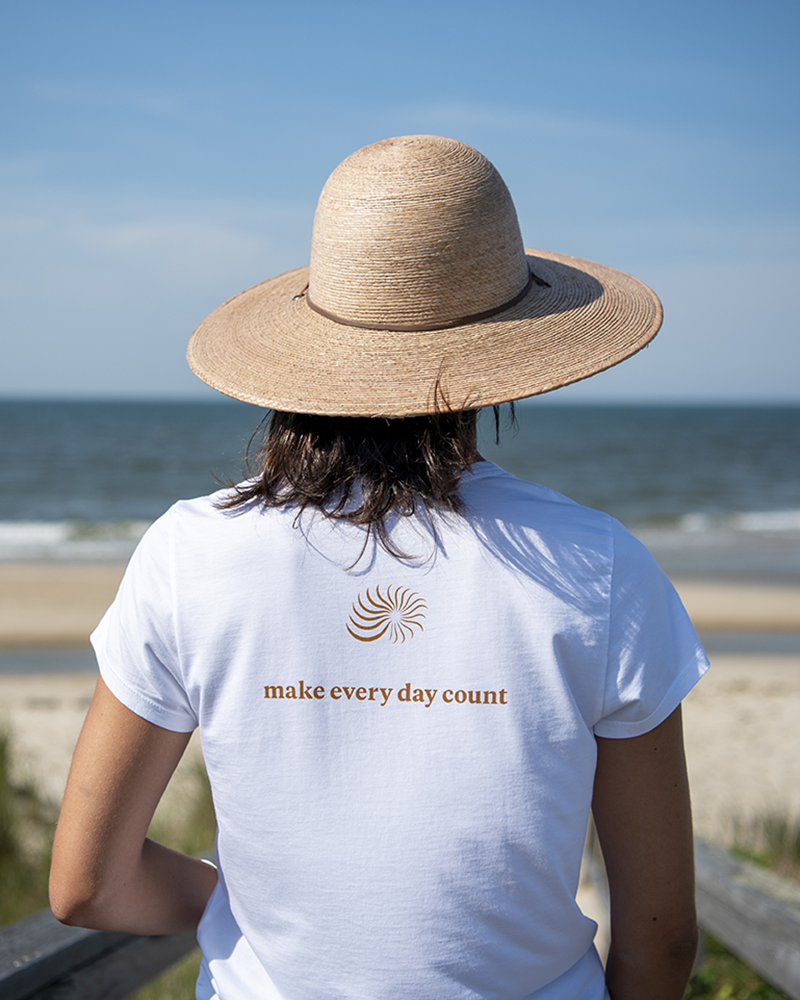 White crew-neck graphic tee with orange spiral emblem and 'make every day count'