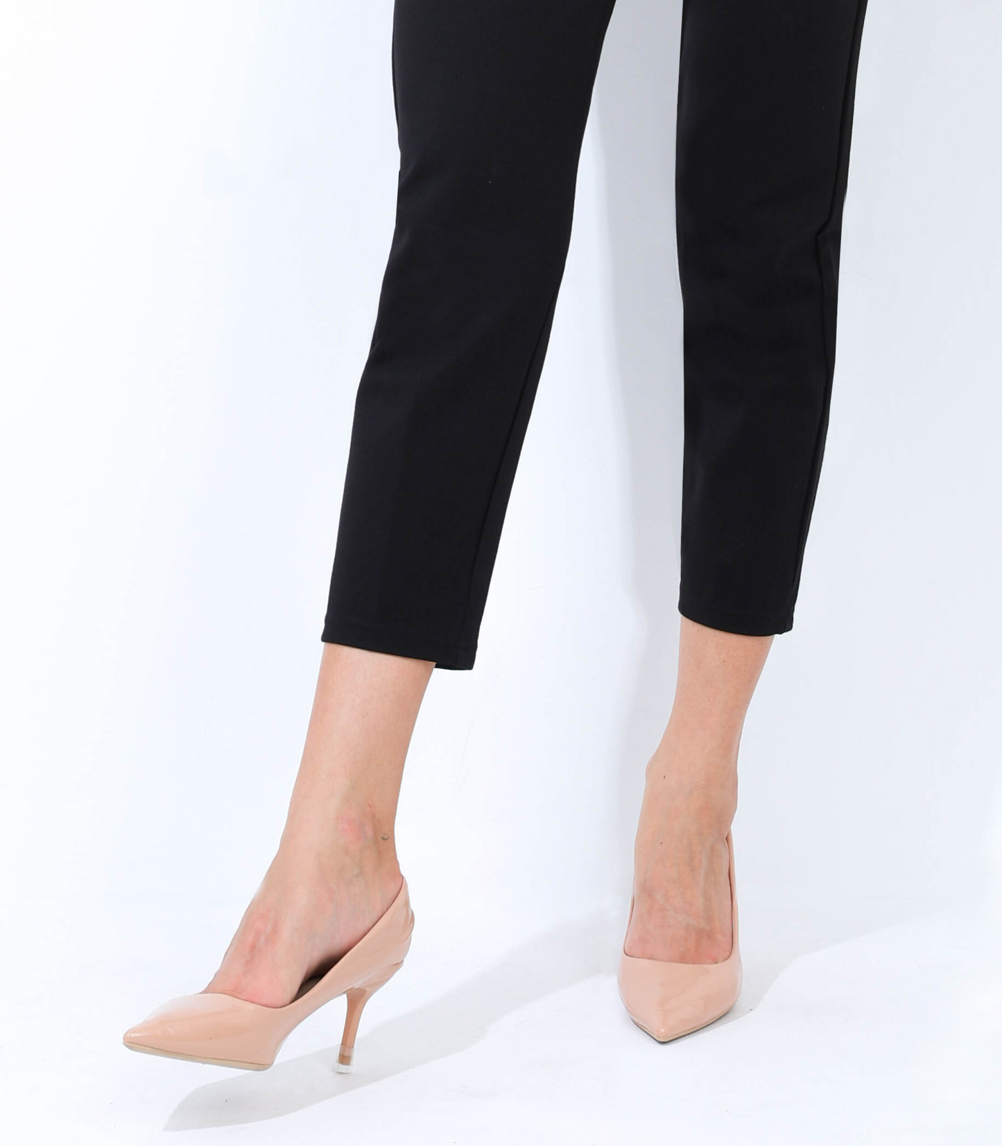 Person wearing black pants and beige high-heeled shoes on a white background