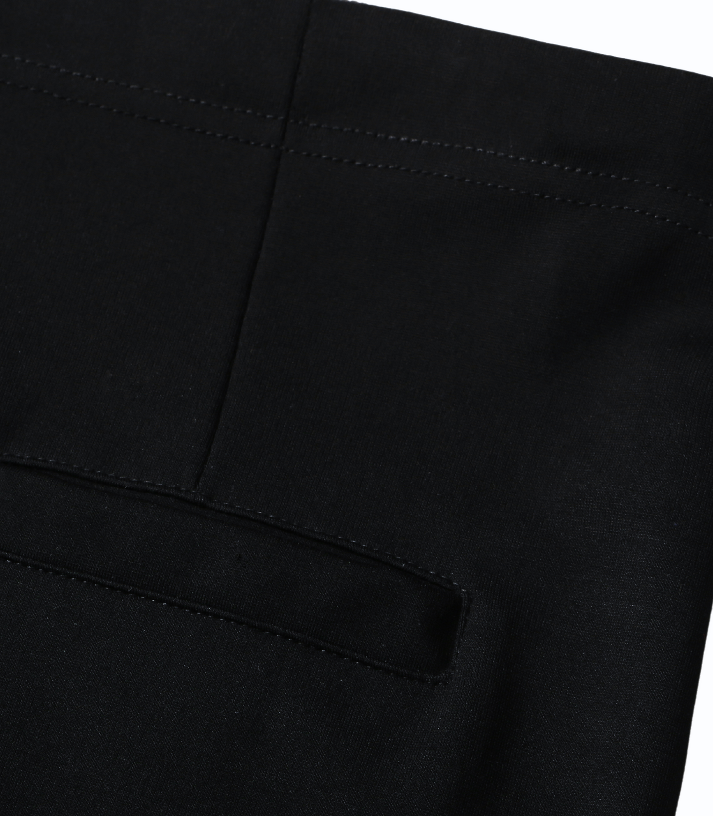 Close-up of black pants with a pocket detail on a white background