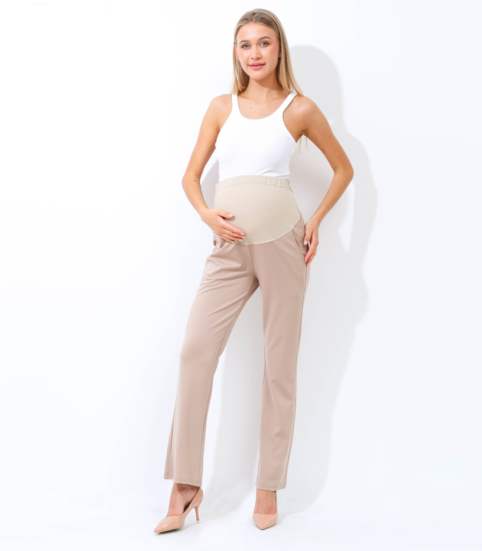 Woman wearing a white top and beige pants against a white background