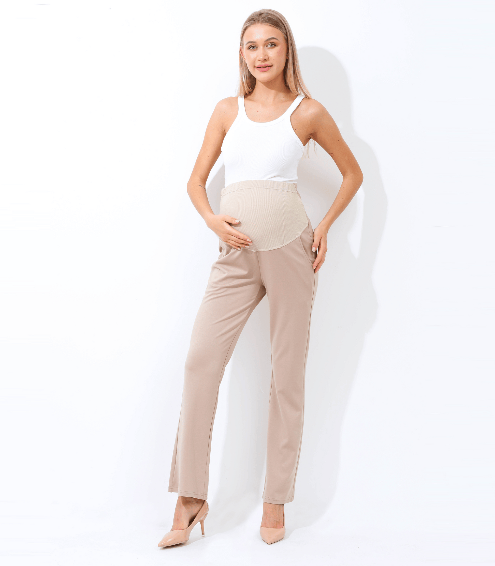 Woman wearing a white top and beige pants against a white background