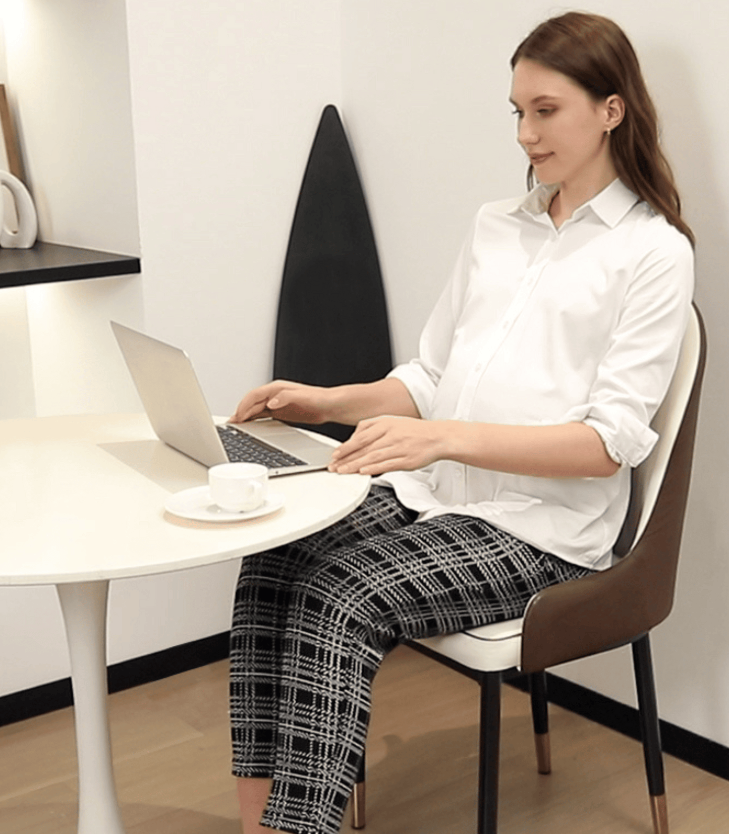 Woman sitting at a desk using a laptop in a minimalistic office setting