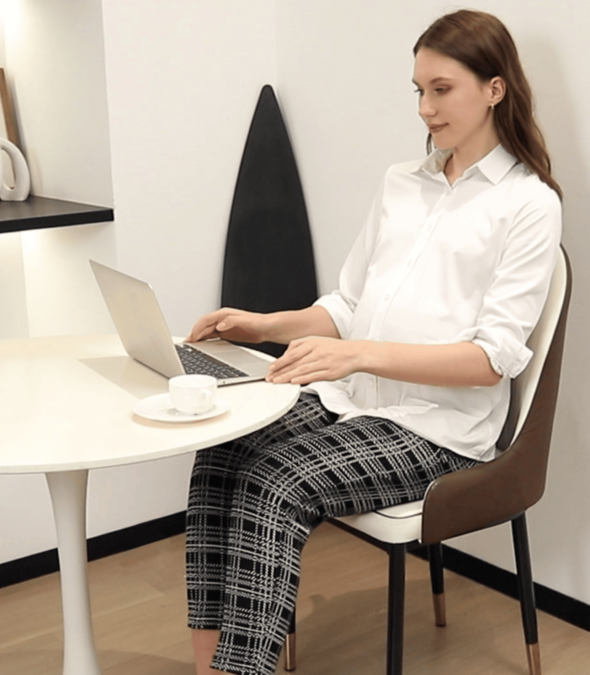 Woman sitting at a desk using a laptop in a minimalistic office setting