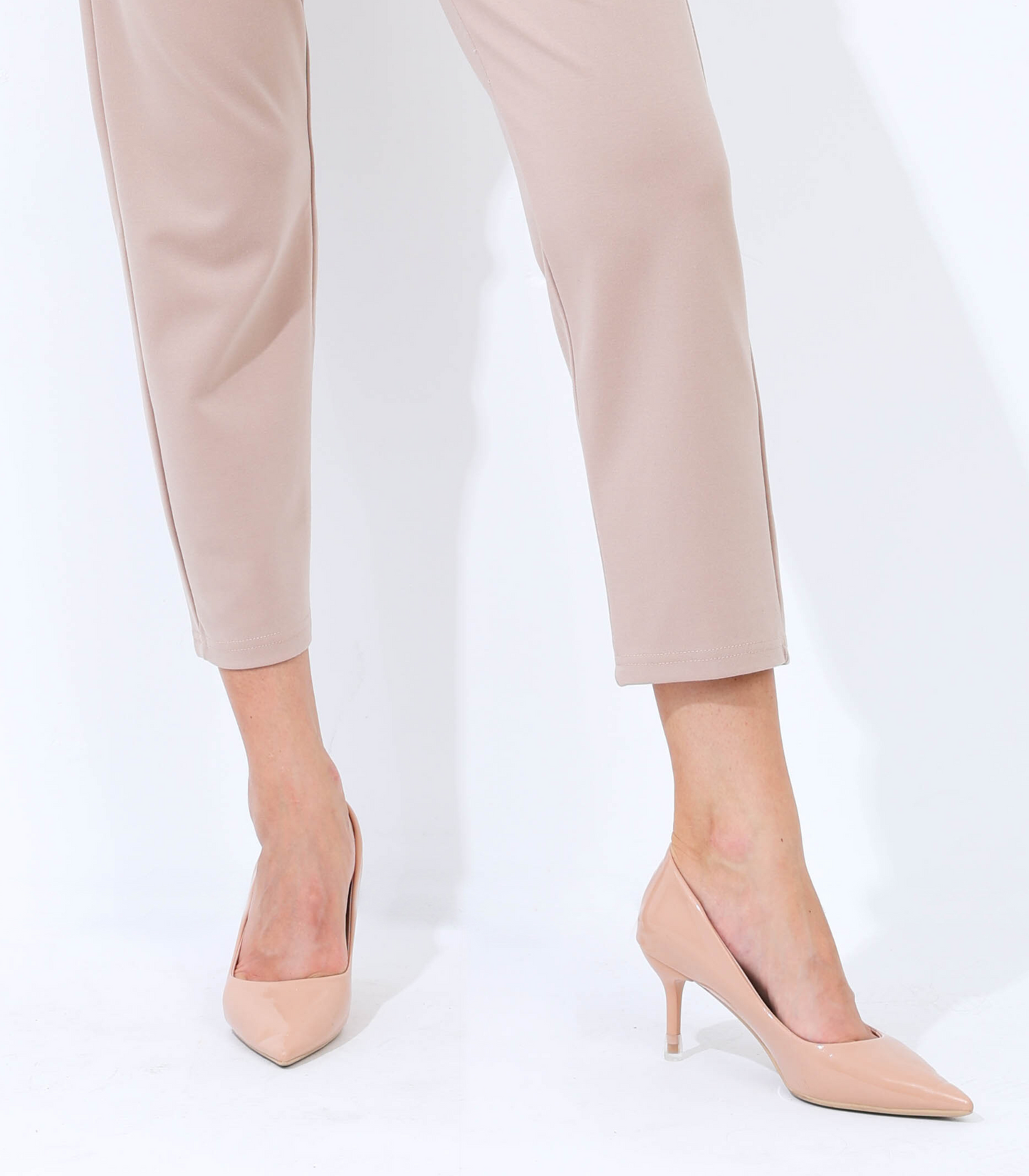 Beige high-heeled shoes worn with beige pants on a white background