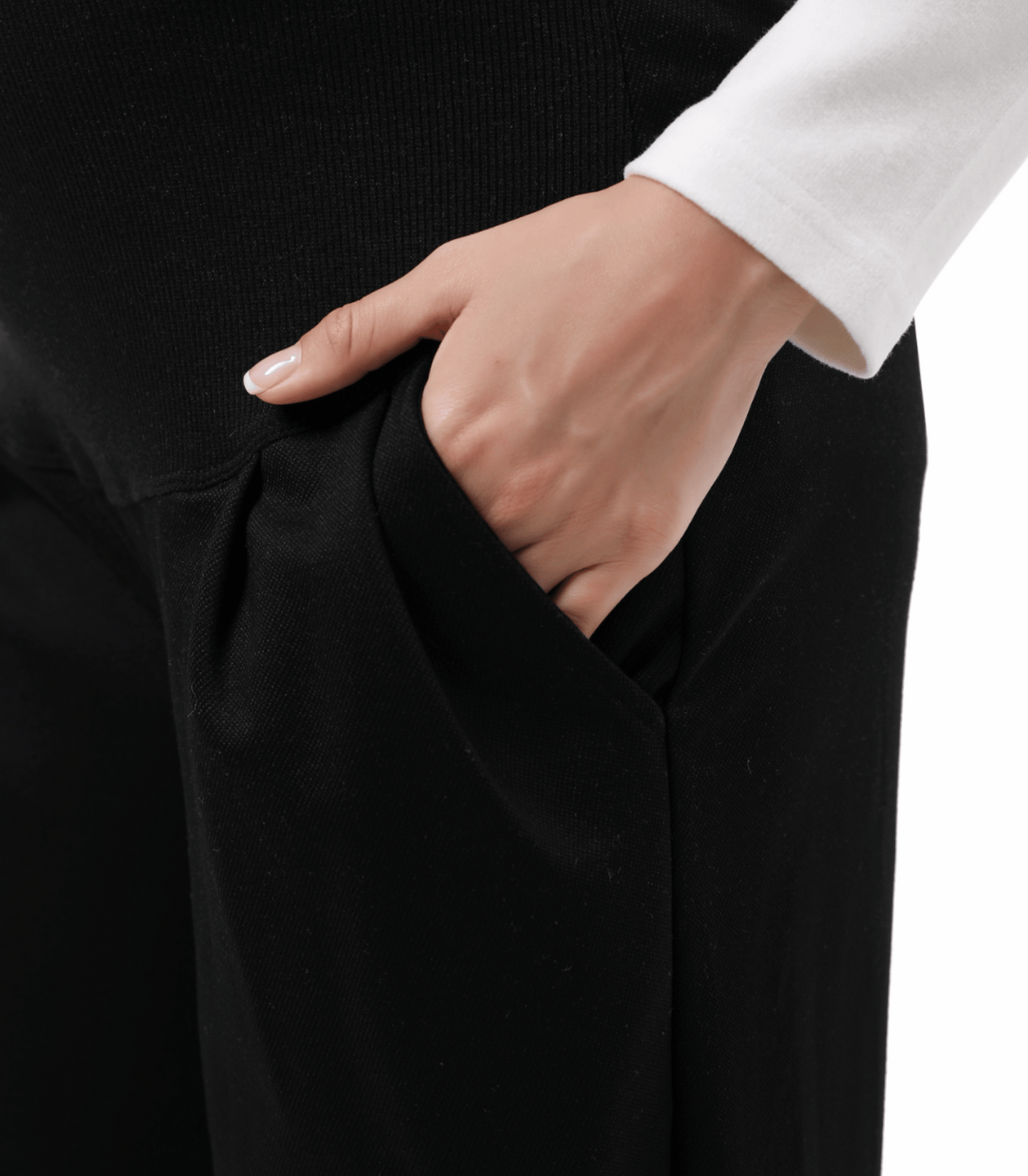 Person wearing black pants with a hand in the pocket against a neutral background