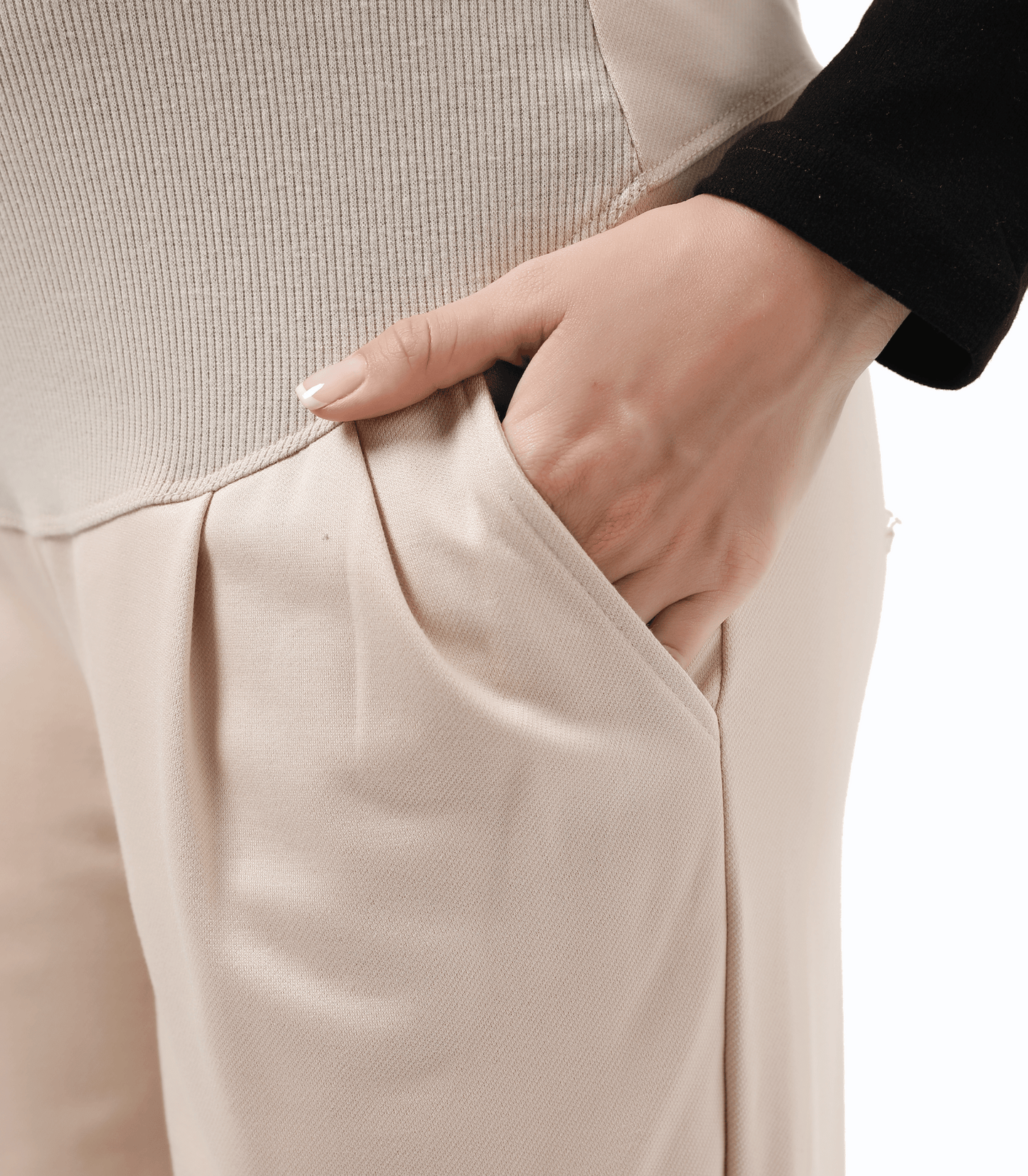 Close-up of beige pants with a hand adjusting the waistband on a white background