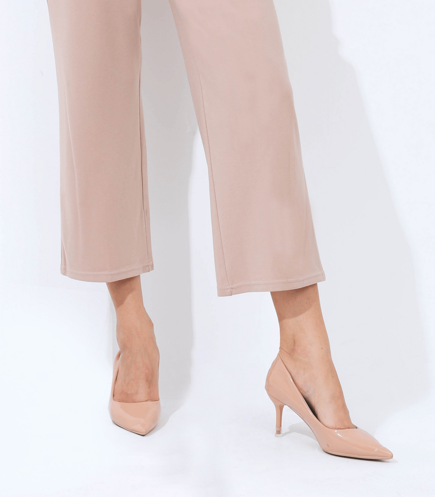 Beige high-heeled shoes worn with beige pants on a white background