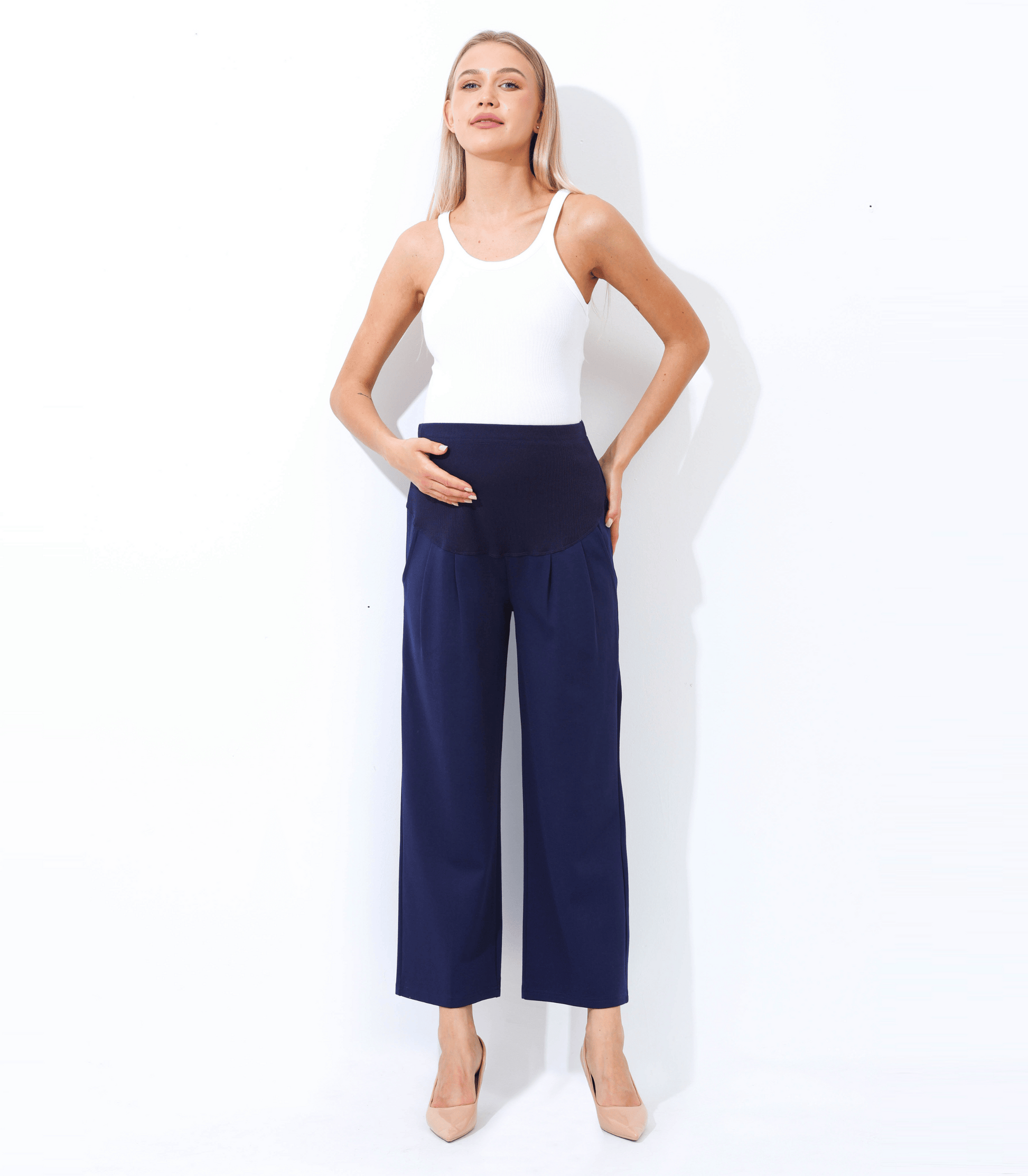 Woman wearing a white top and navy wide-leg pants on a white background