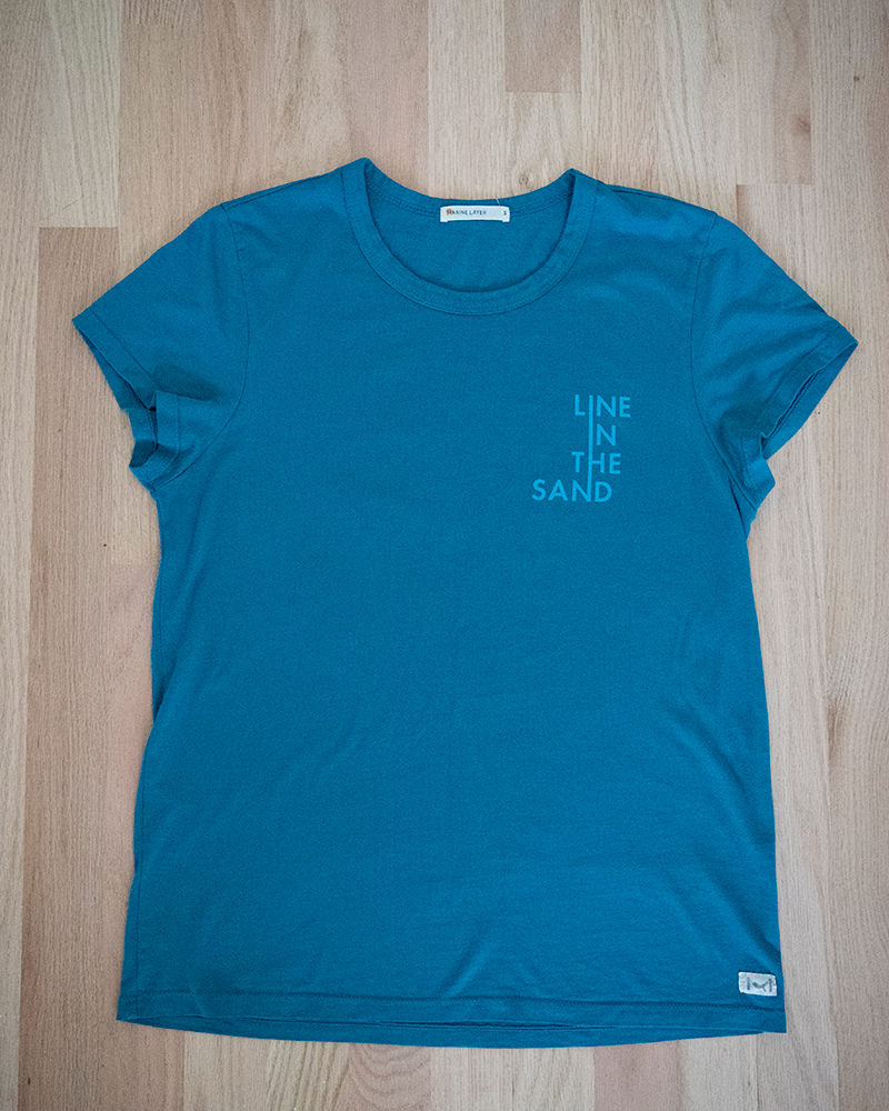 Teal front T-shirt with crew neck and small 'LINE IN THE SAND' chest print