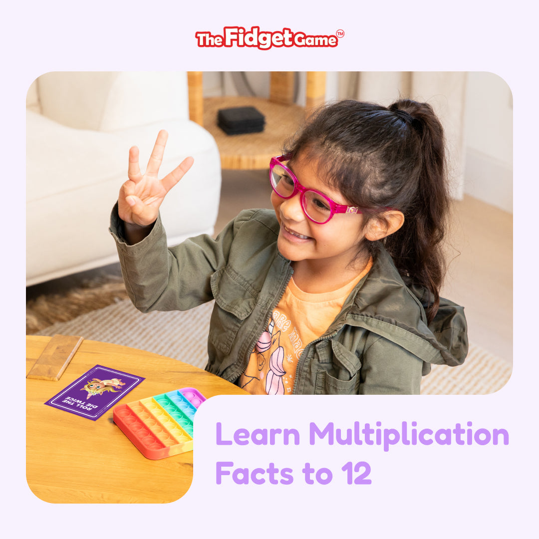 Multiplication learning flashcards on a table with a child holding a card