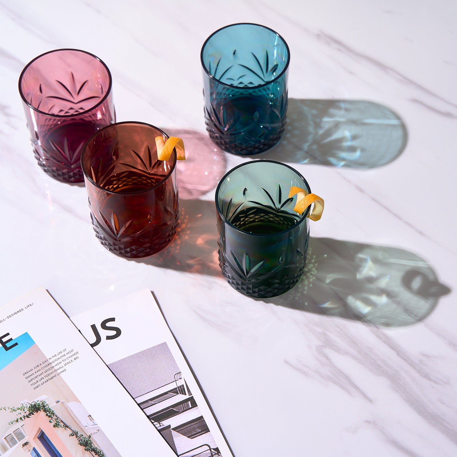 Four acrylic lowball glasses with jewel-tone colors and cut leaf pattern; tumbler shape