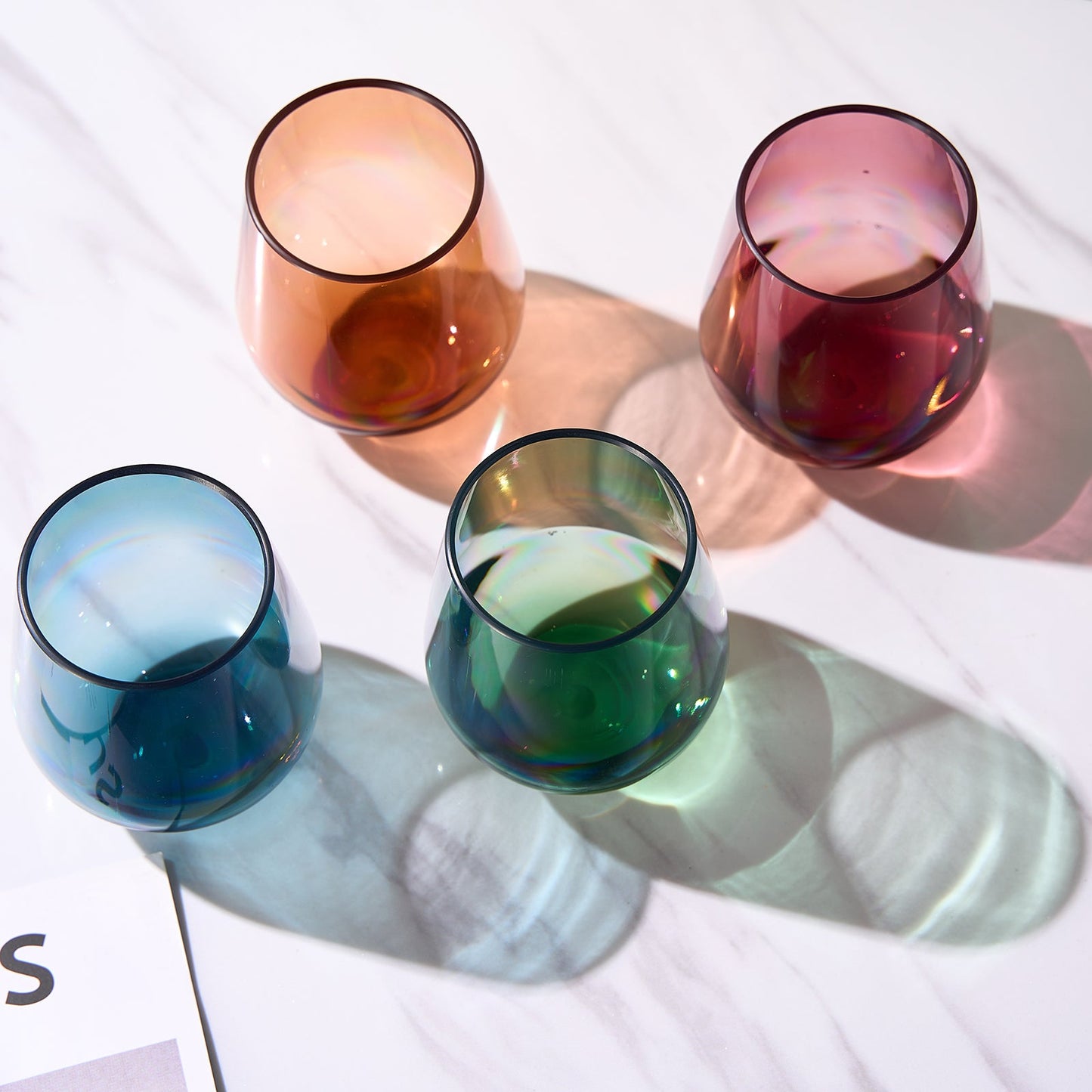 Four stemless acrylic wine glasses arranged top-down: blue, green, amber, and red.