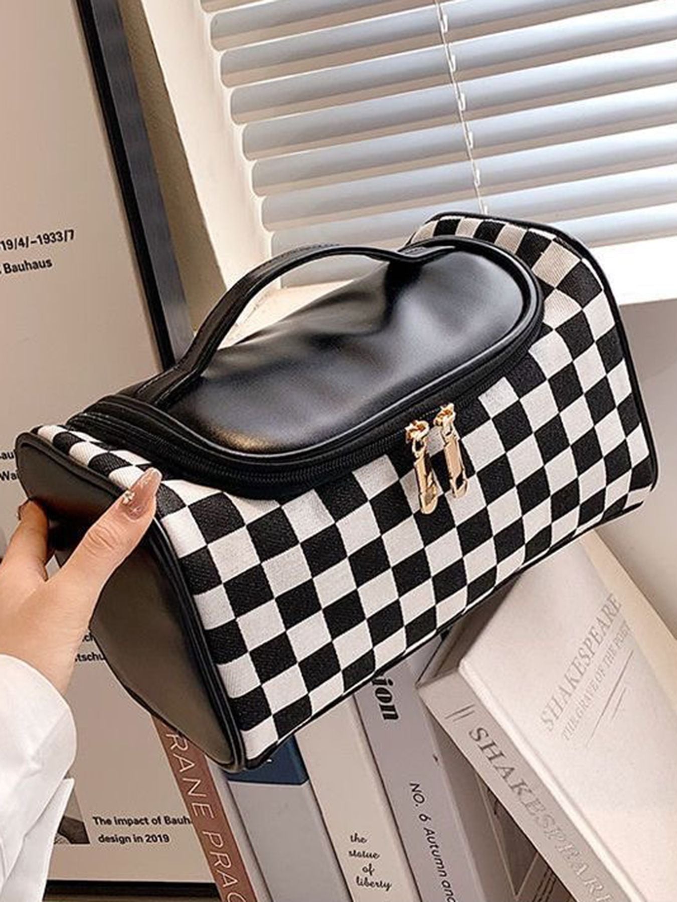 Plaid cosmetic bag with black-and-cream check pattern, brown handle and zipper closure
