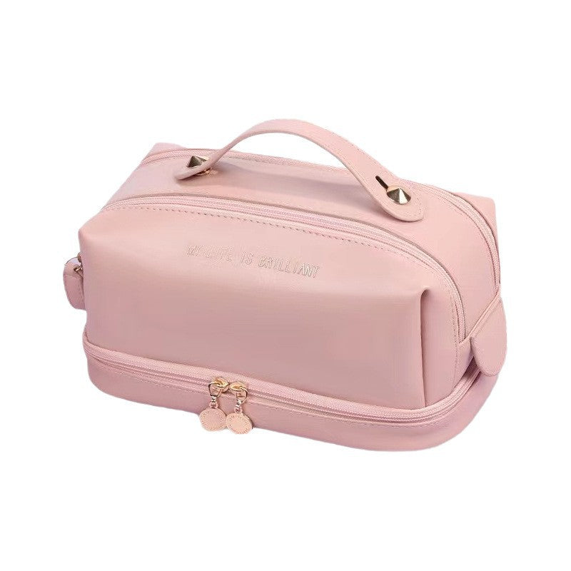 Pink double-zip makeup bag with top handle, studded strap loops, and front zipper
