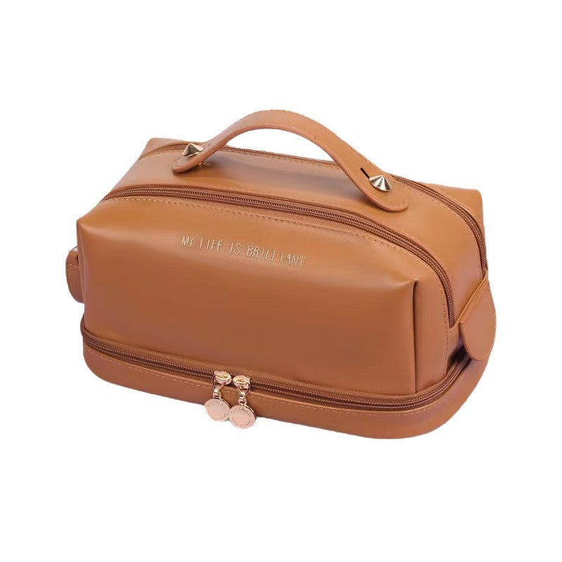 Light brown double-zip cosmetic bag with top handle, front zipper, and tassel charm