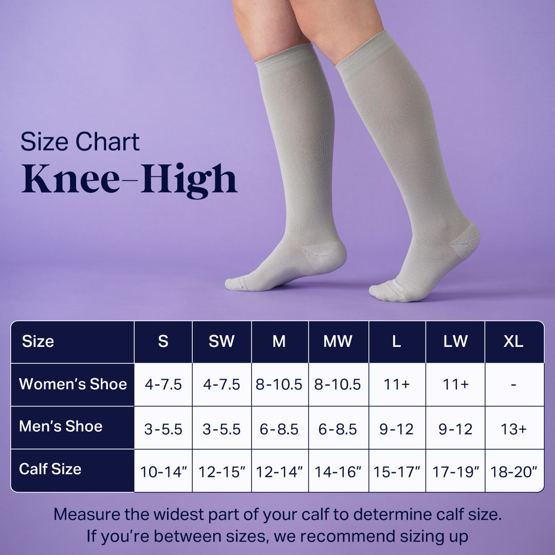 Beige knee-high compression socks pair on feet, size chart background